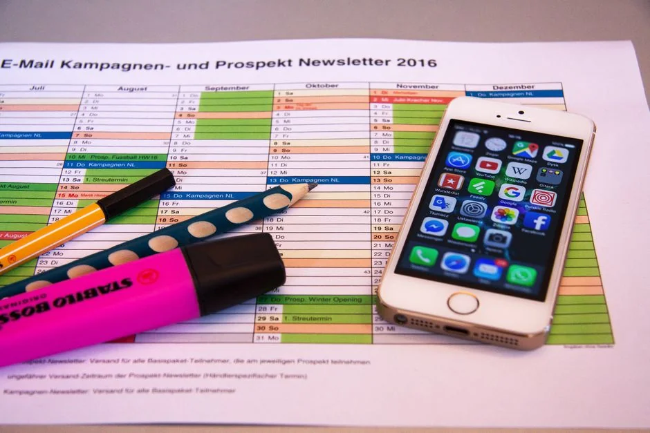 A modern office setup featuring a laptop and a whiteboard schedule for social media platforms.